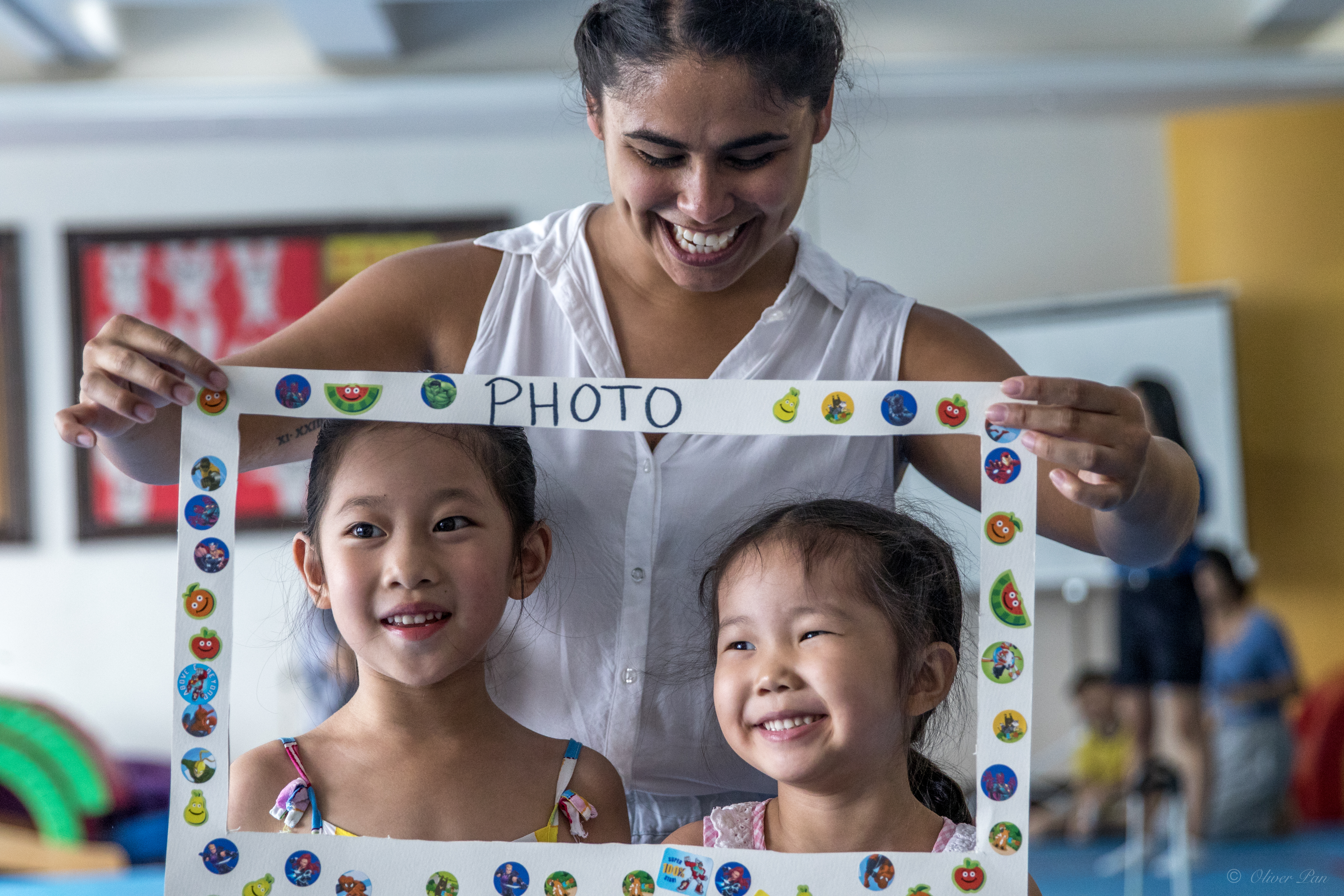 Teacher holding paper frame over children smiling